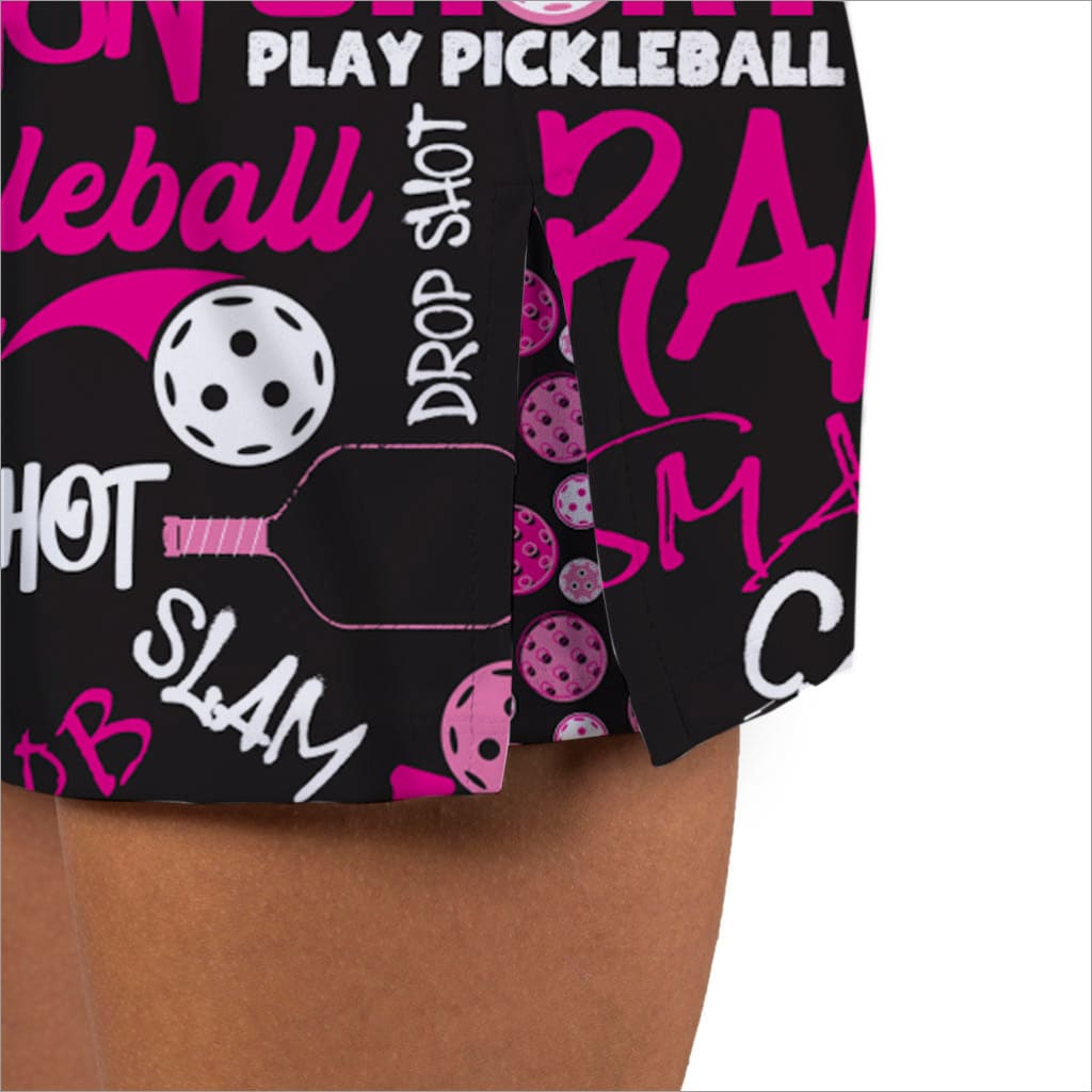 Pickleball-themed shorts with pink and white text and graphics on a black background.