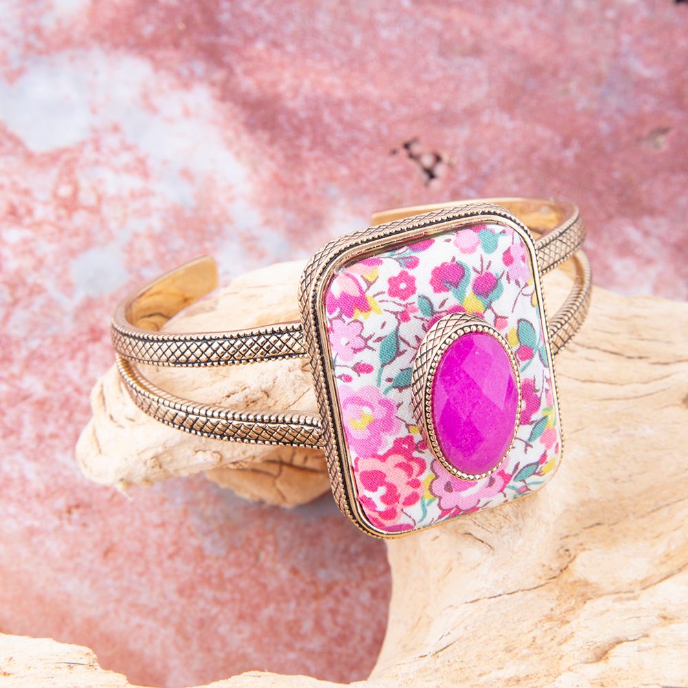 Bracelet with floral patterned clasp and pink stone on a textured surface
