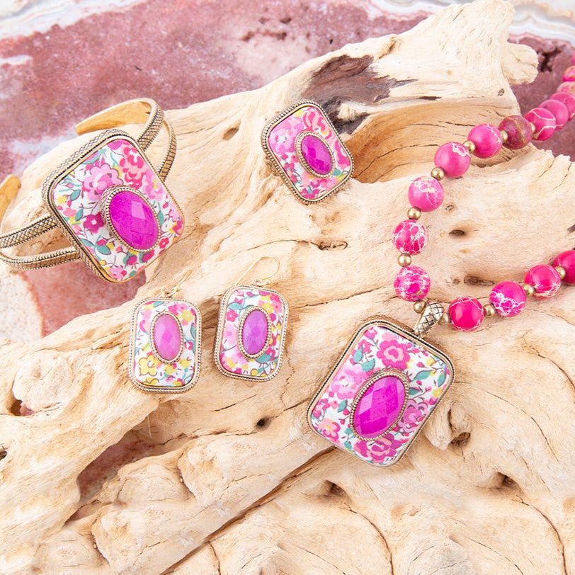 Set of pink floral jewelry on a textured surface