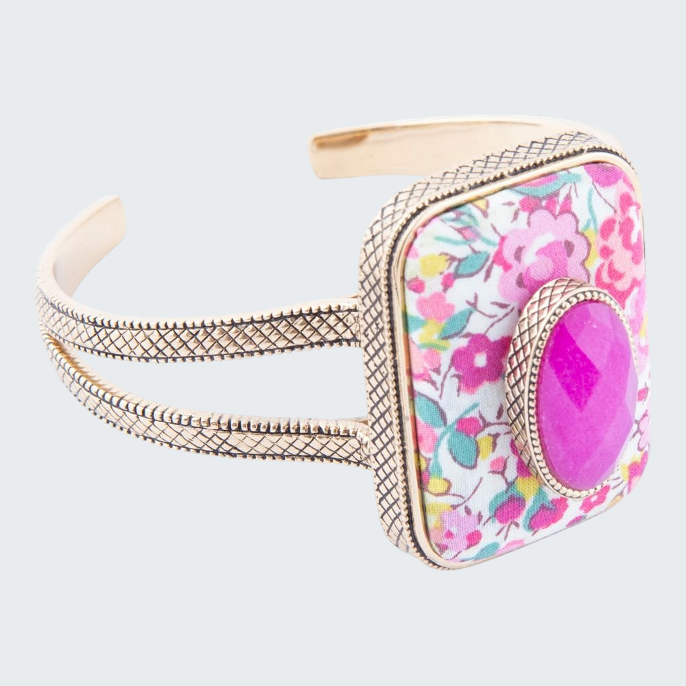 Bangle with floral pattern and pink stone on a white background