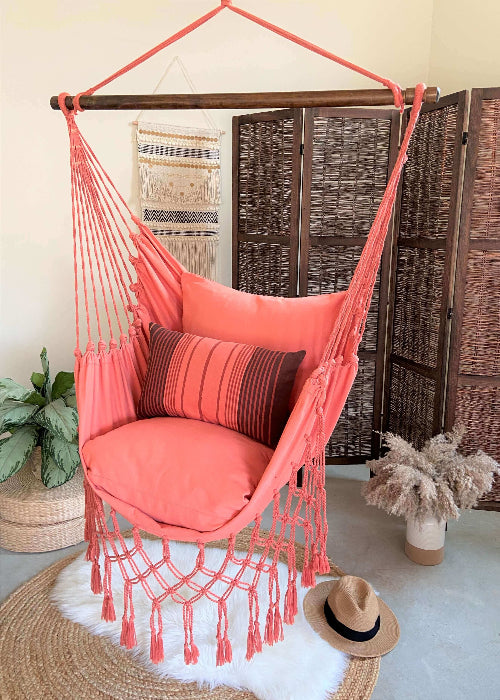 Coral hammock chair with decorative pillows in a room setting.