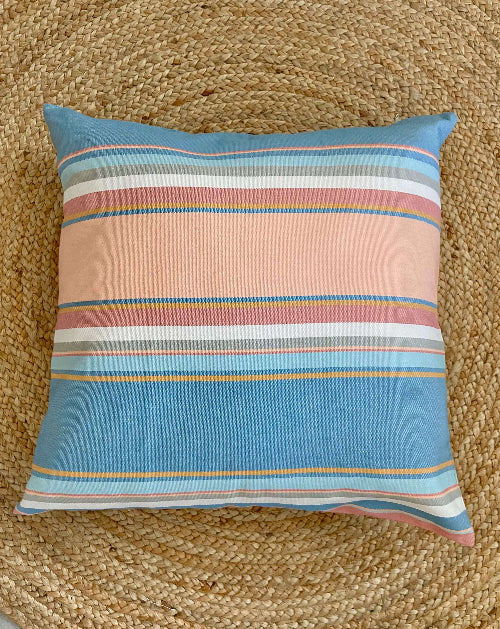 Striped pillow with blue and pink colors on a textured brown surface
