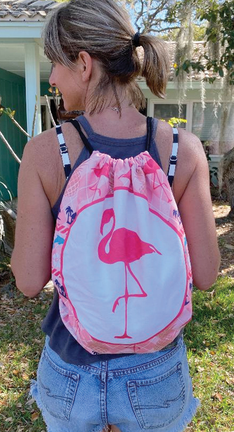 Person wearing a drawstring bag with a flamingo design outdoors.