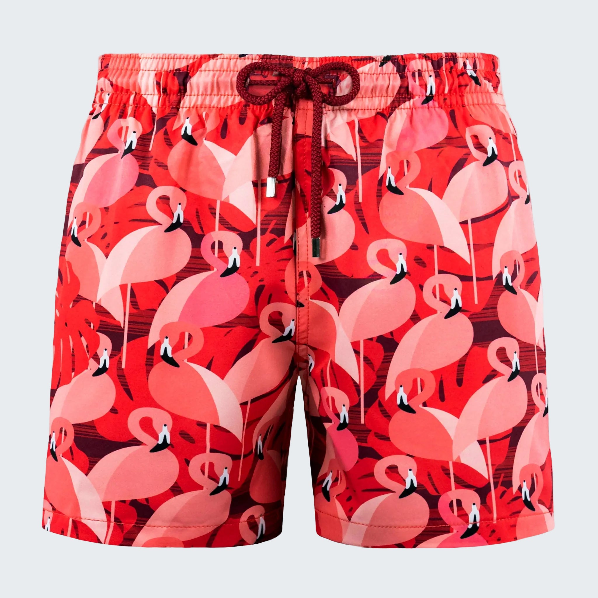 Red swim shorts with pink flamingo pattern on a white background