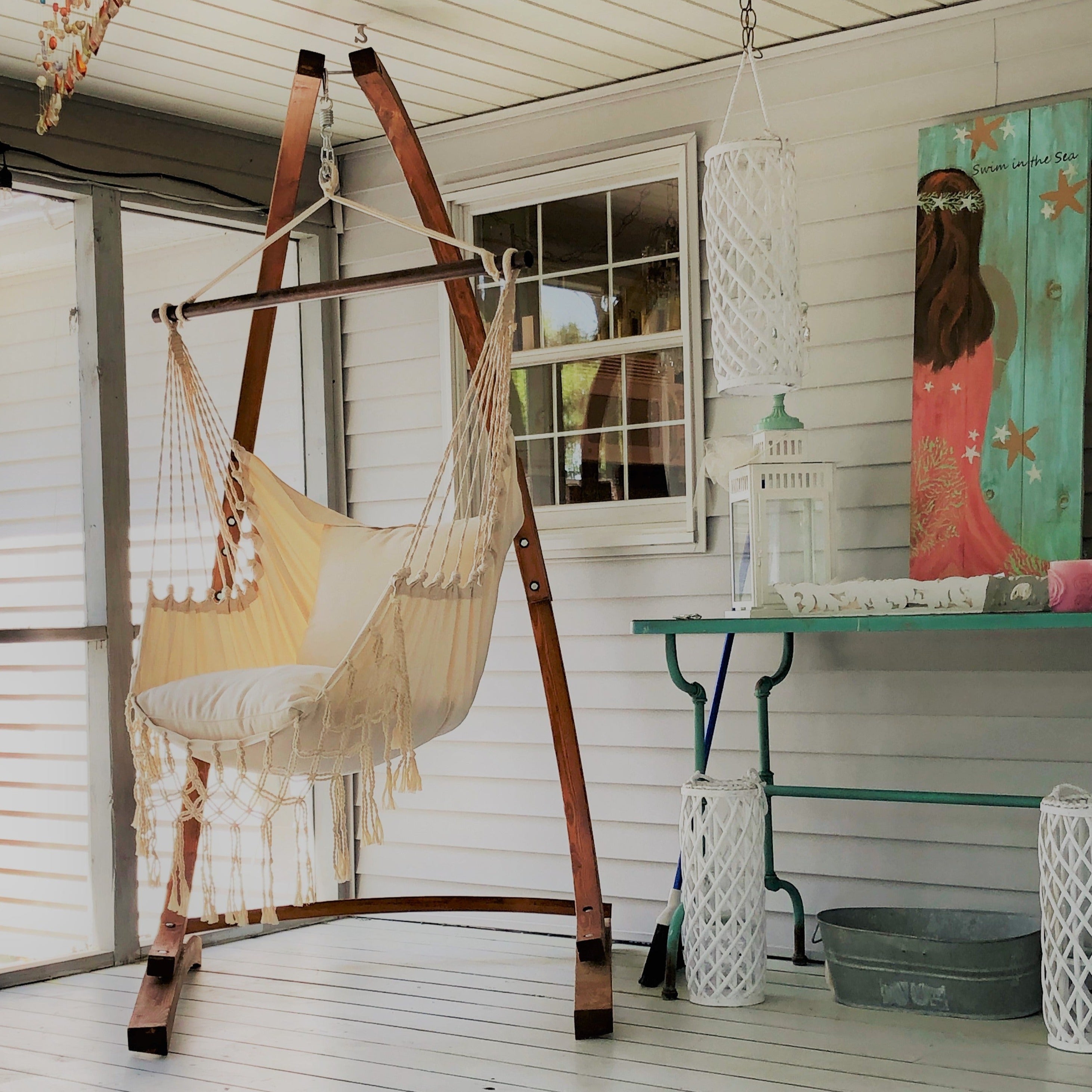 Hammock on a stand in a room with a table and decorative items.