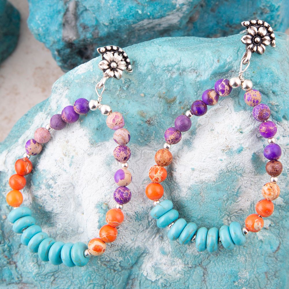 Colorful beaded earrings on a textured blue surface