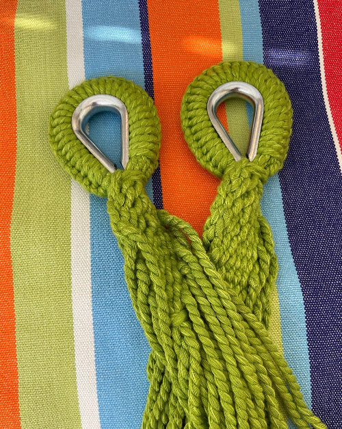 Two green ropes with metal hooks on a colorful striped background
