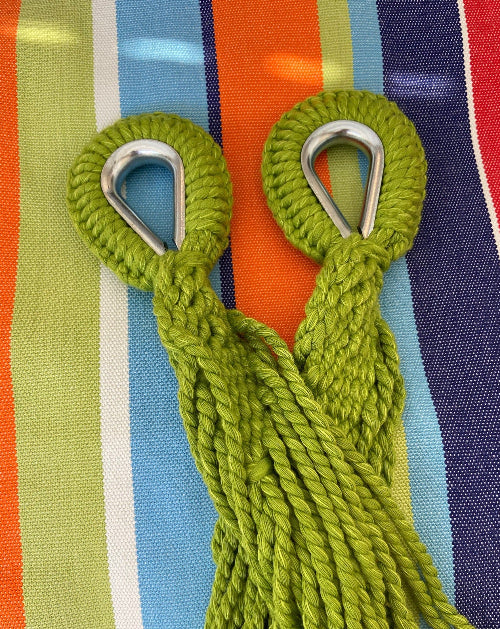 Two green ropes with metal hooks on a colorful striped background
