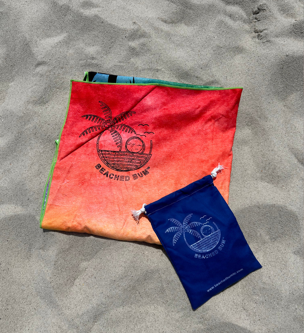Red and blue bags with palm tree design on a sandy surface
