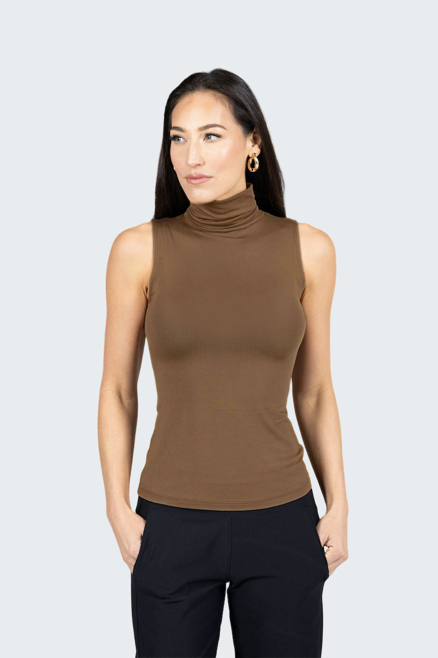 Woman wearing a brown sleeveless turtleneck top against a gray background
