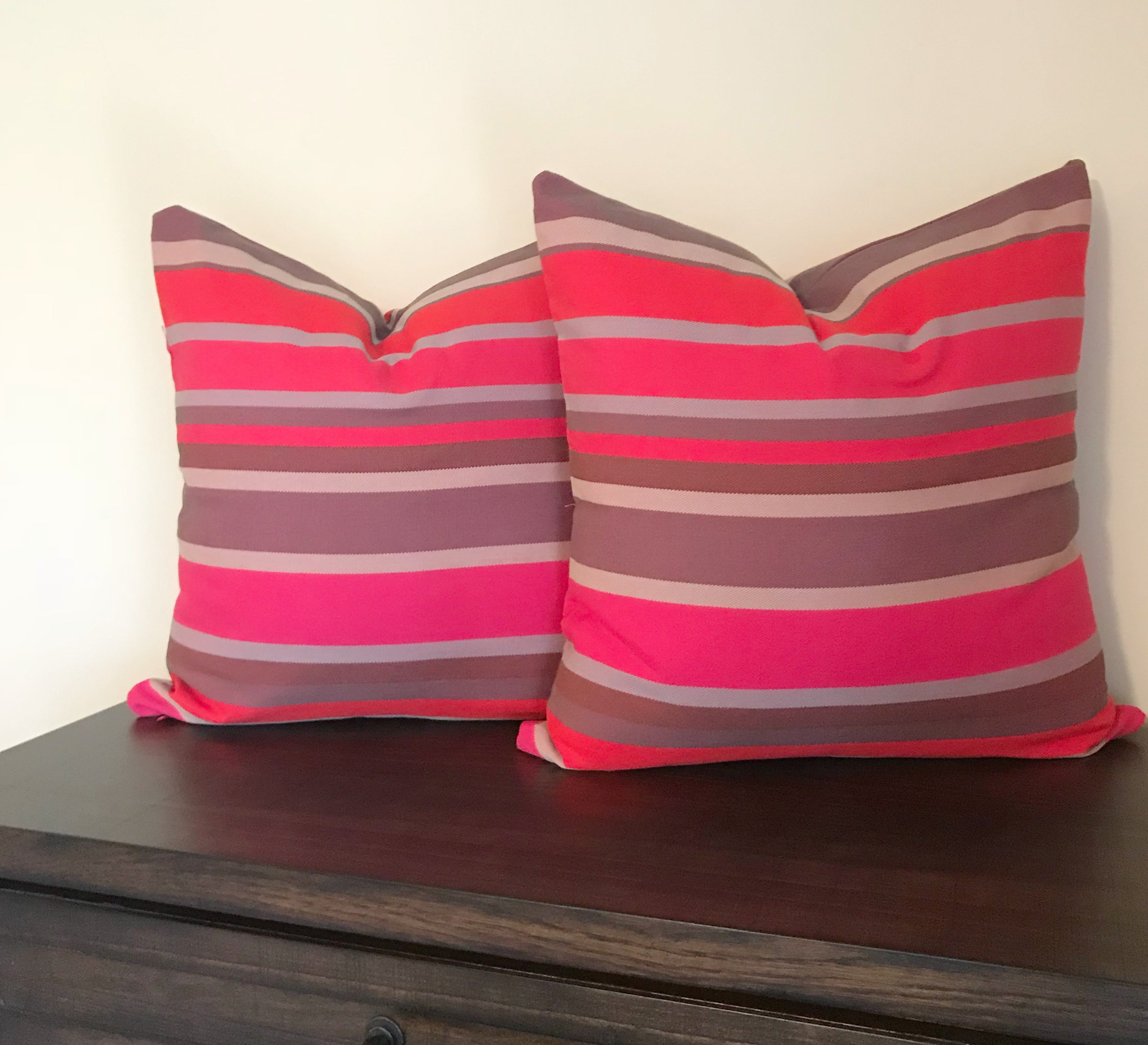 Two striped pillows on a wooden surface with a neutral background