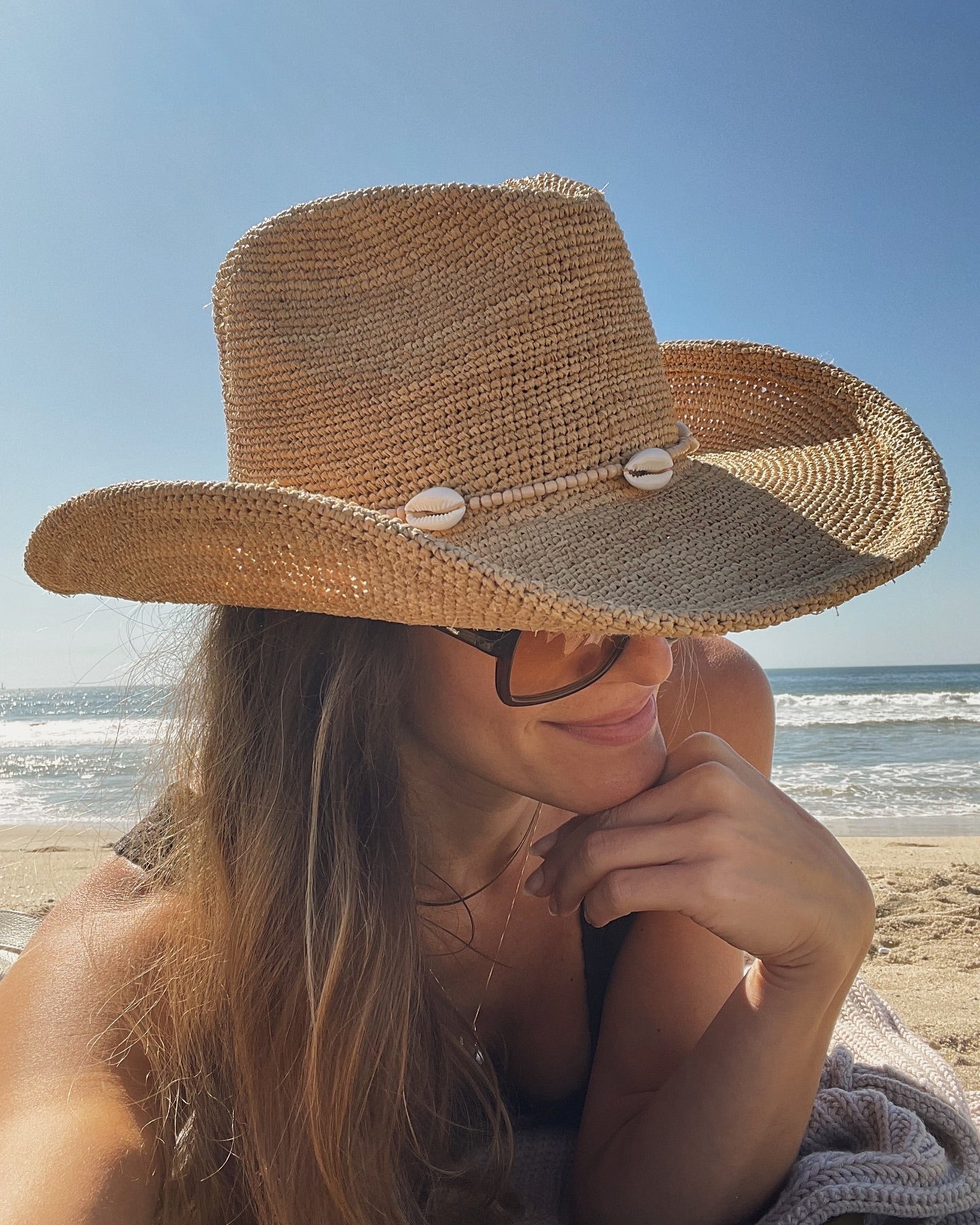 Person wearing a straw hat on a beach with ocean view
