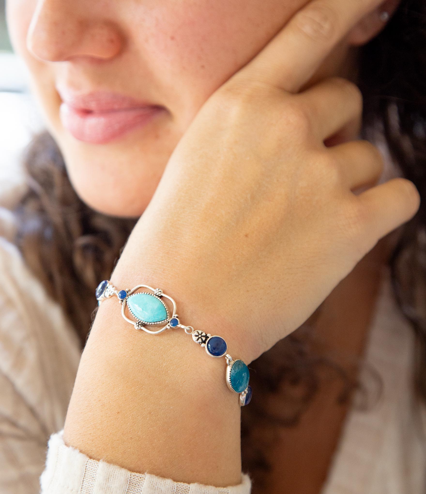 Close-up of a person wearing a turquoise beaded bracelet on a blurred background