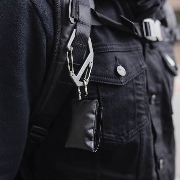Person wearing a black jacket with a carabiner attached to the pocket.