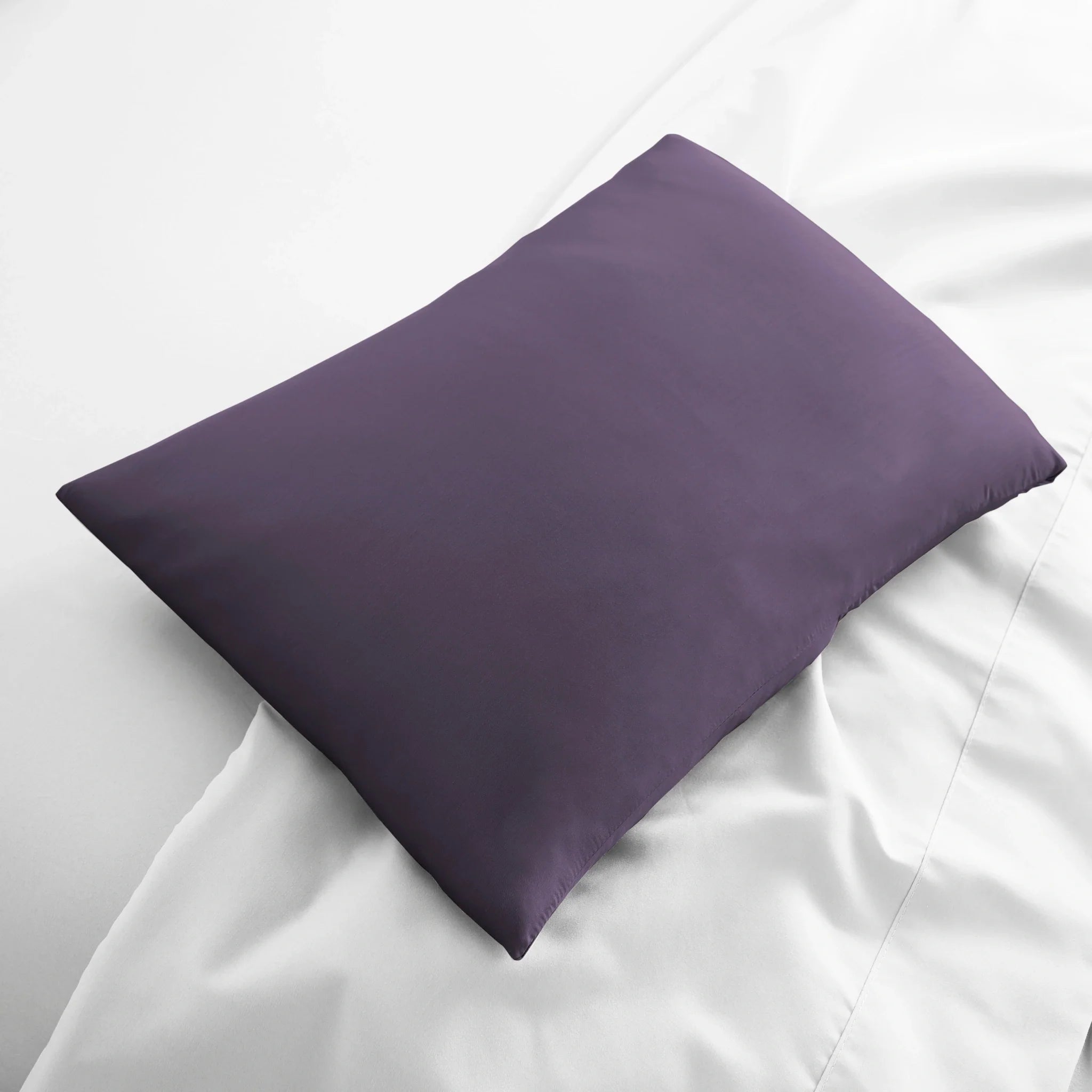 Purple pillow on a white bed