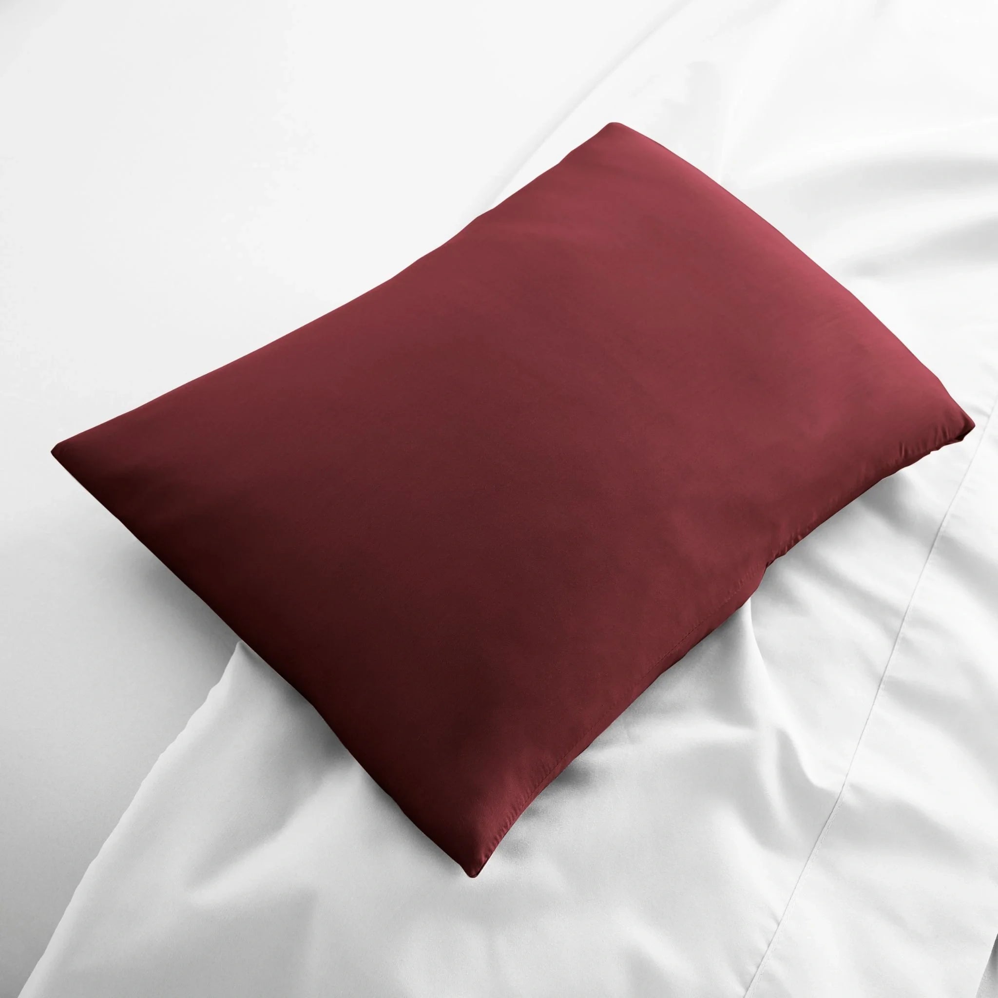 Maroon pillow on a white bed