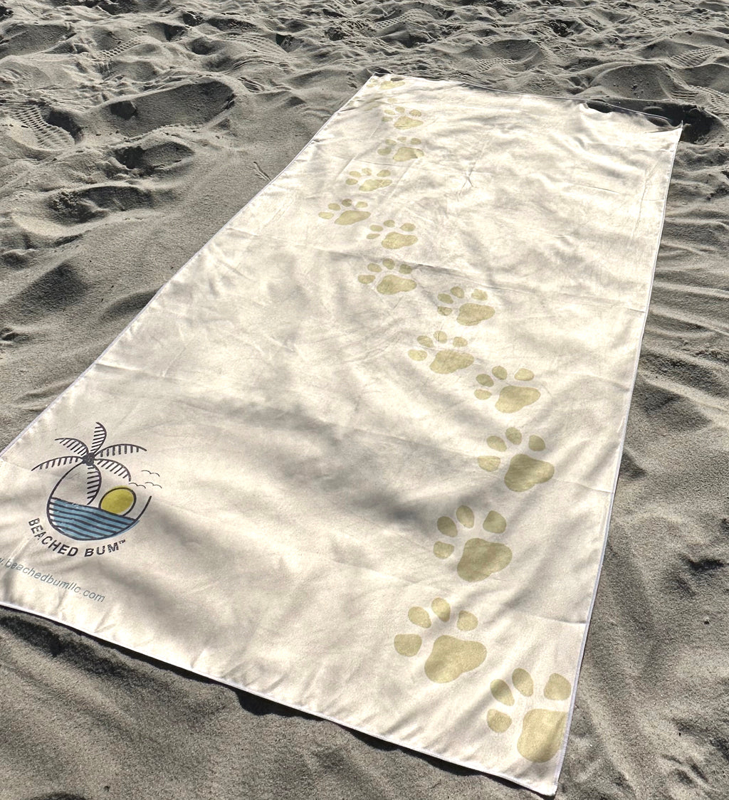 Beach towel with paw prints and a logo on sand