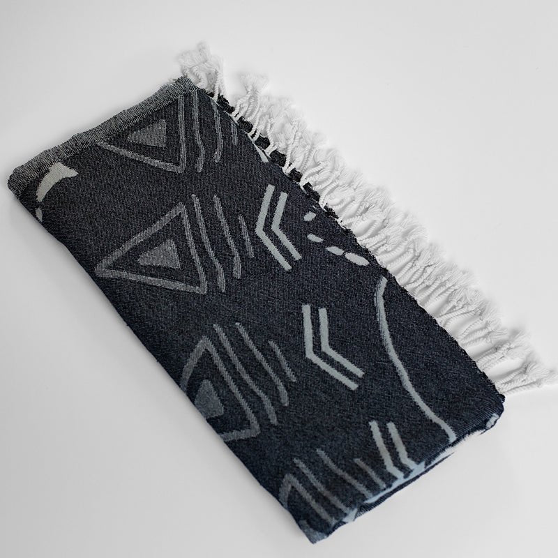 Black and white patterned blanket with frayed edges on a light gray background