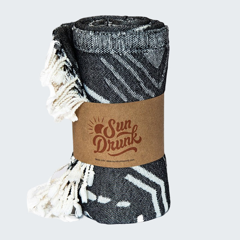 Folded black and white patterned blanket with a 'Sun Drunk' label on a white background
