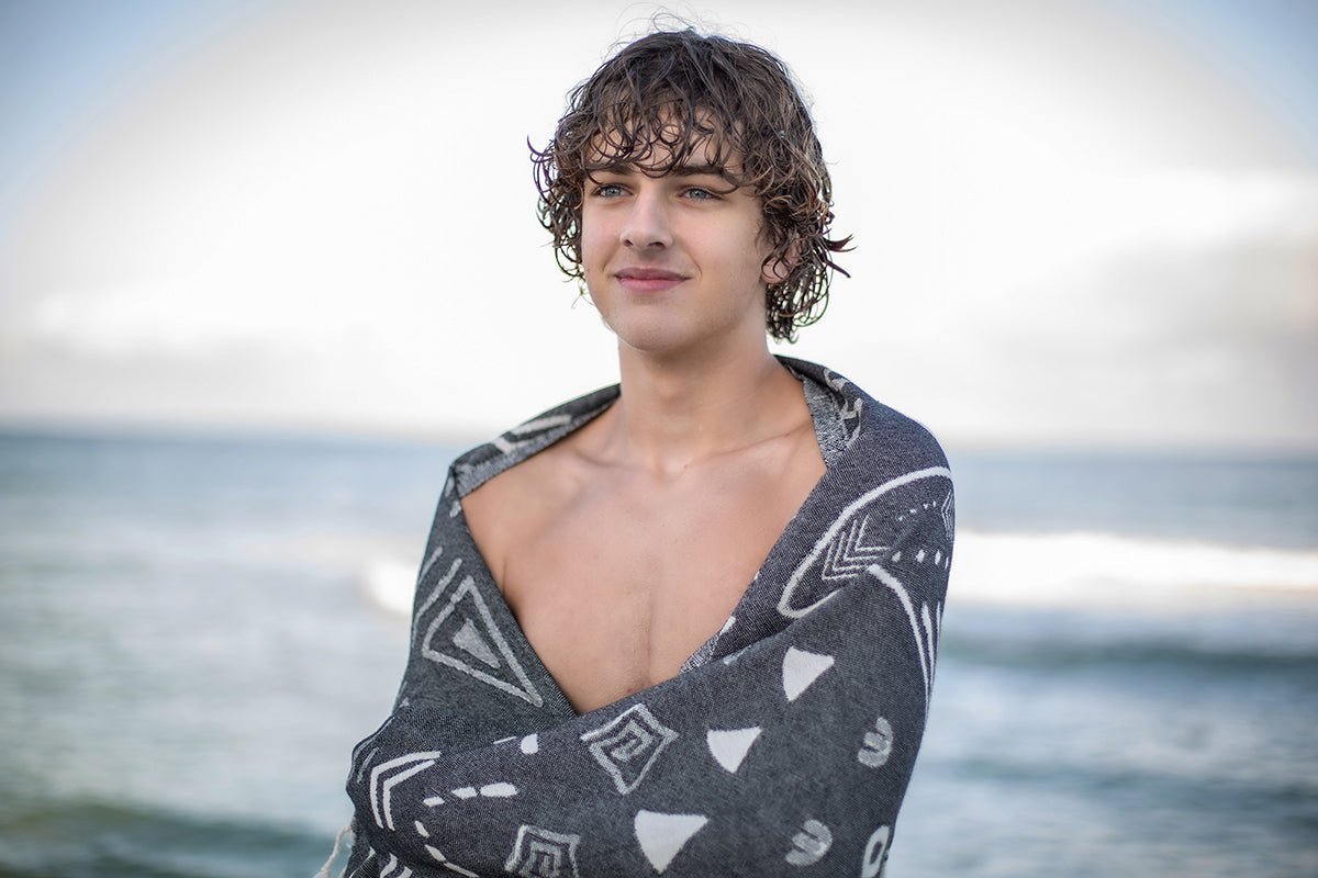 Person wrapped in a patterned towel on a beach