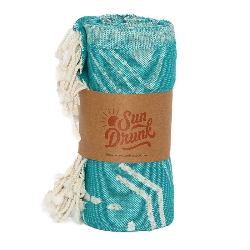 Teal towel with white patterns and a 'Sun Drunk' label on a white background