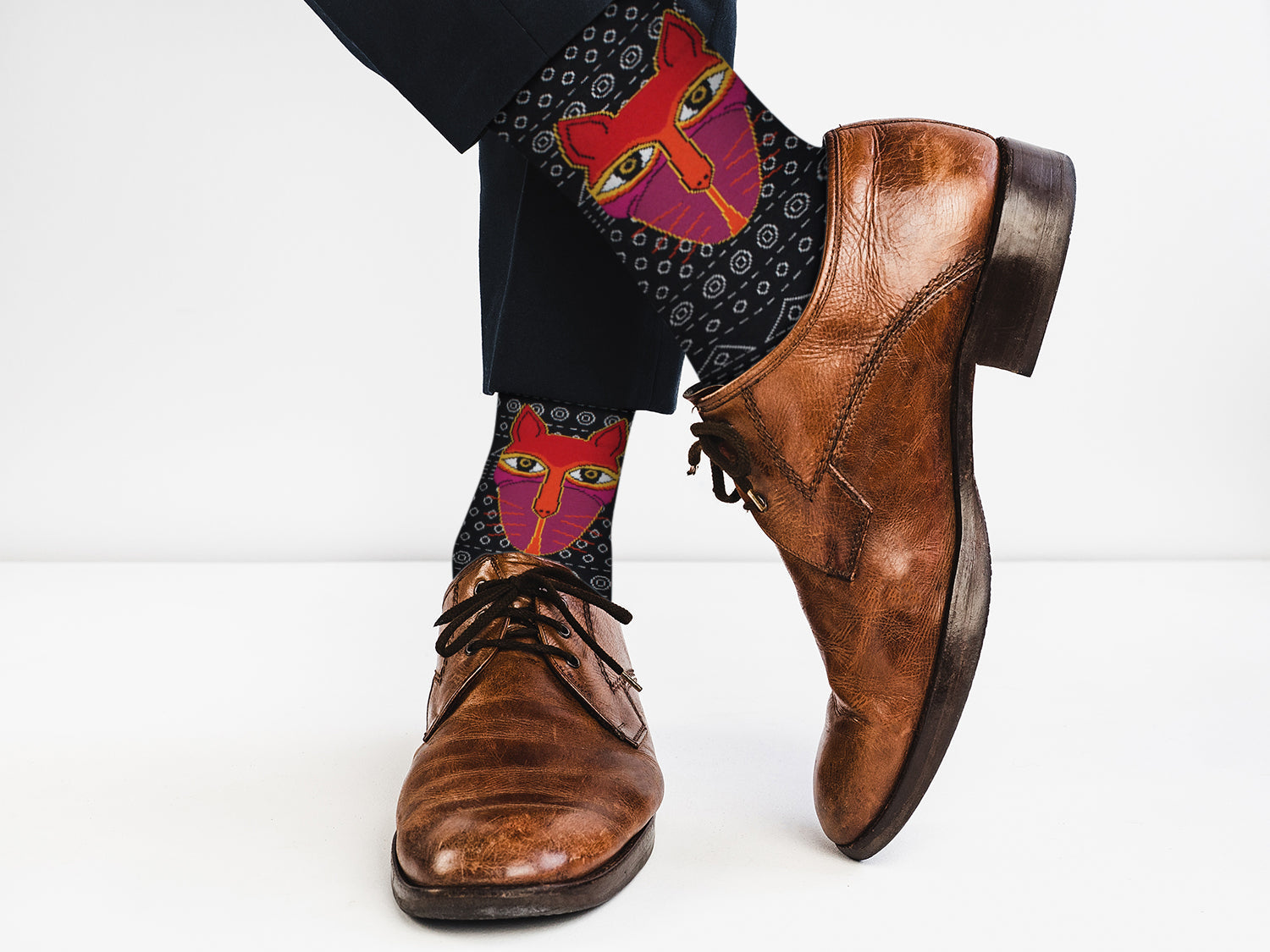 Brown leather shoes with colorful patterned socks on a white background