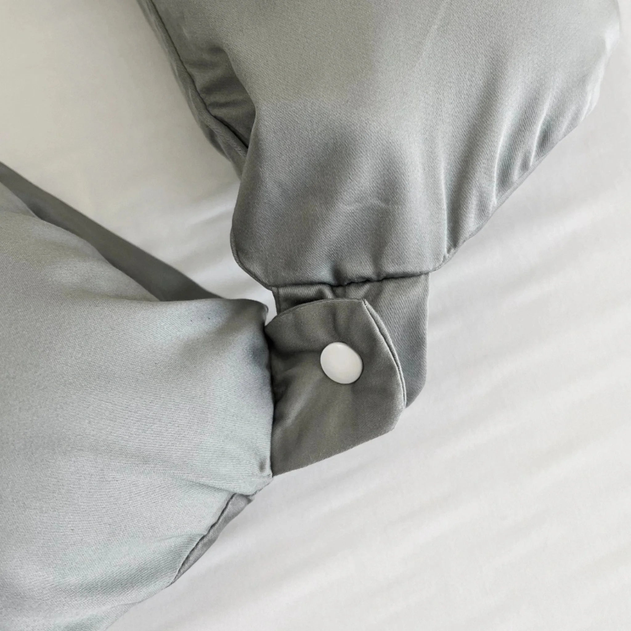 Gray satin pillowcase with a white button on a white background