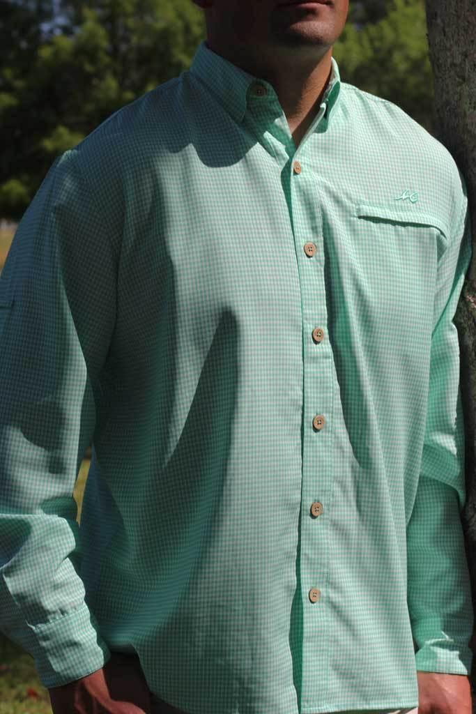 Person wearing a light green checkered shirt with buttons outdoors