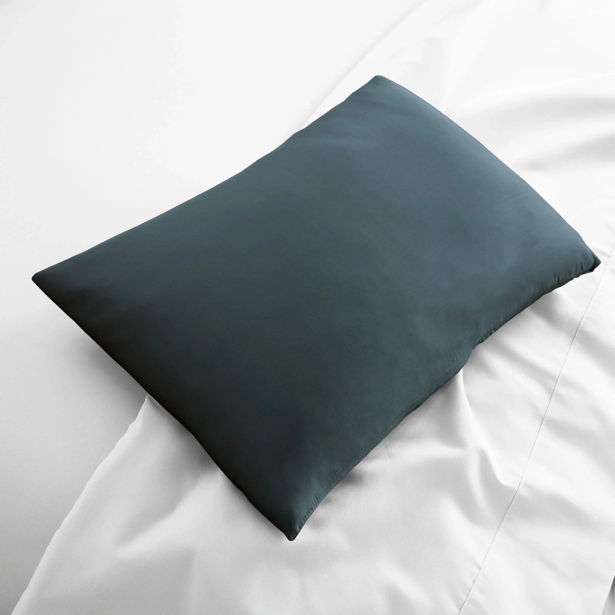 Dark blue satin pillow on a white bed
