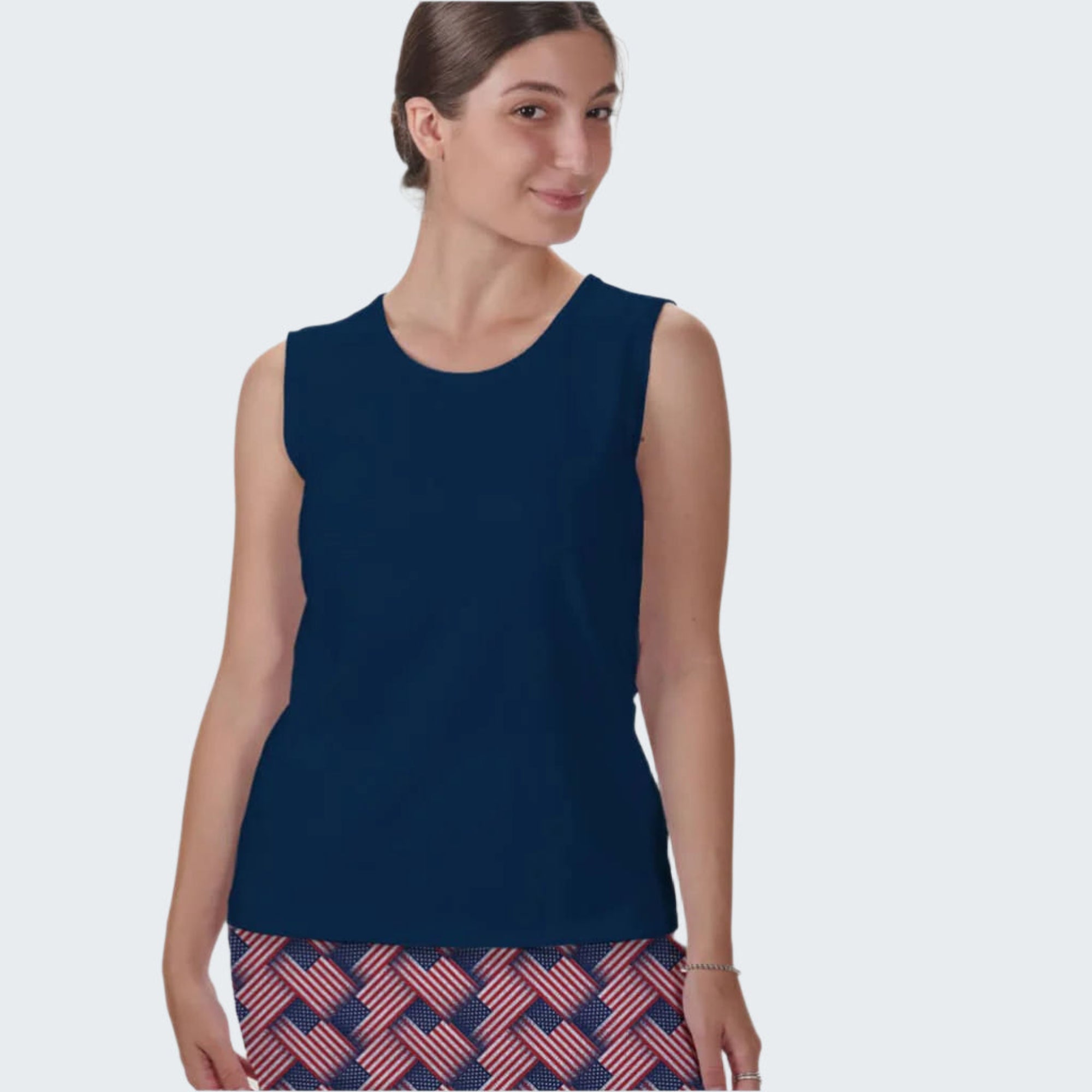 Woman wearing a navy sleeveless top and patterned skirt on a white background