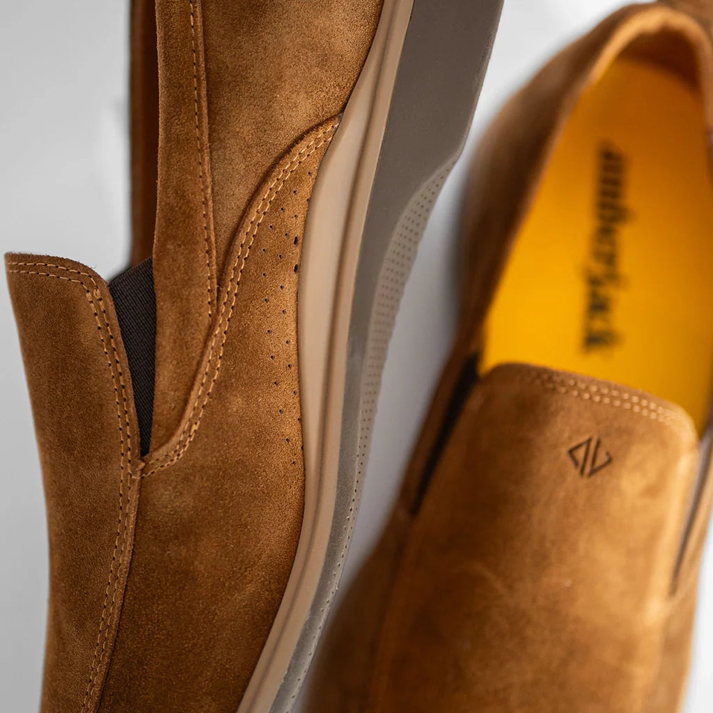 Brown suede shoes with a visible brand logo on a light gray background