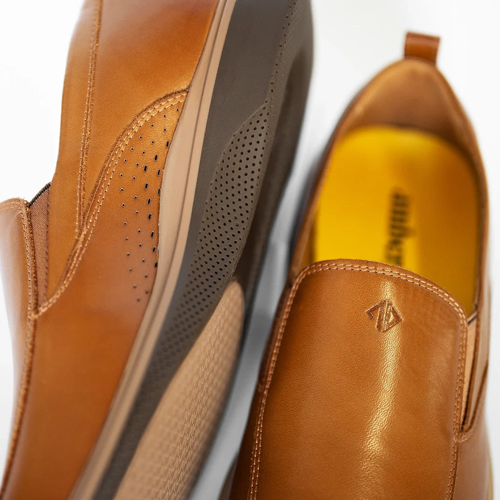 Close-up of brown leather shoes with a visible brand logo on a white background