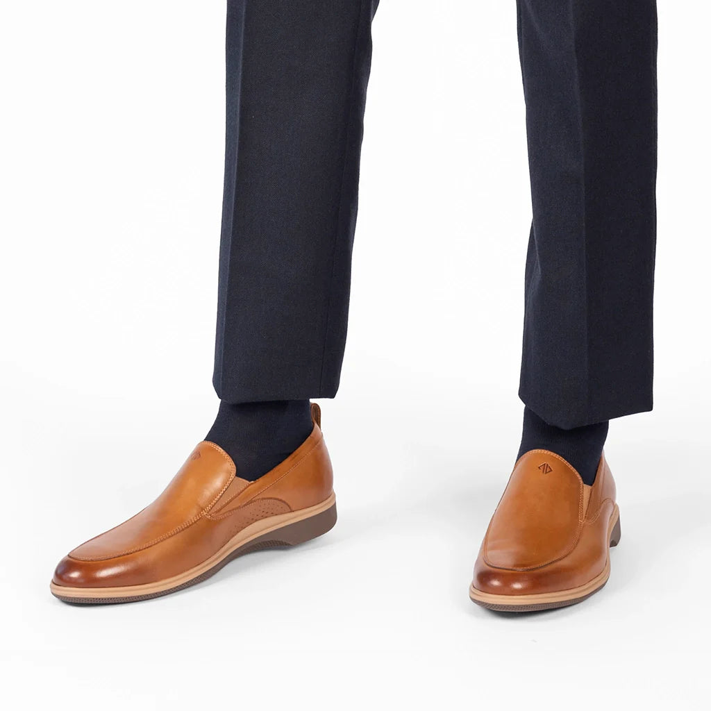 Brown leather shoes worn with navy pants on a white background