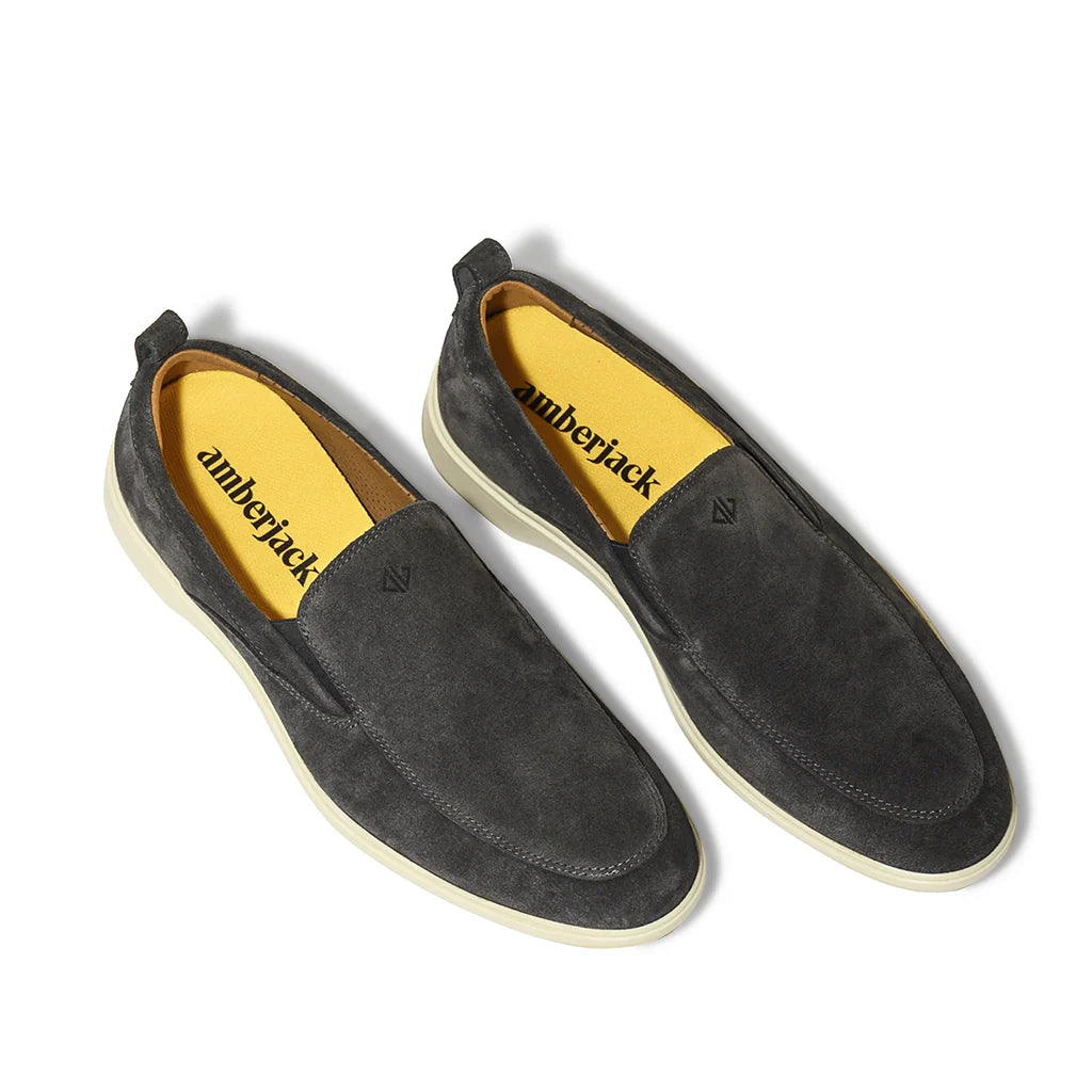 Pair of black loafers with yellow interior on a white background