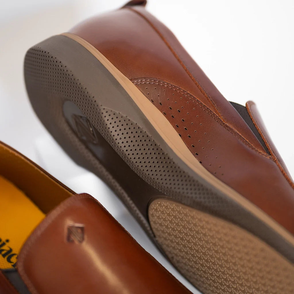 Close-up of brown leather shoes with a visible brand logo on a white background