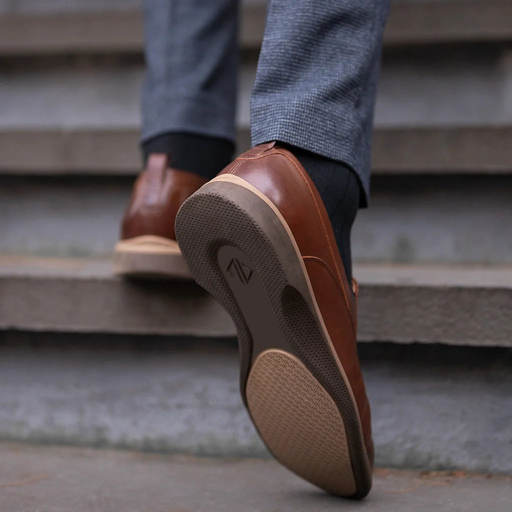 Brown leather shoes with a visible brand logo on a concrete step.