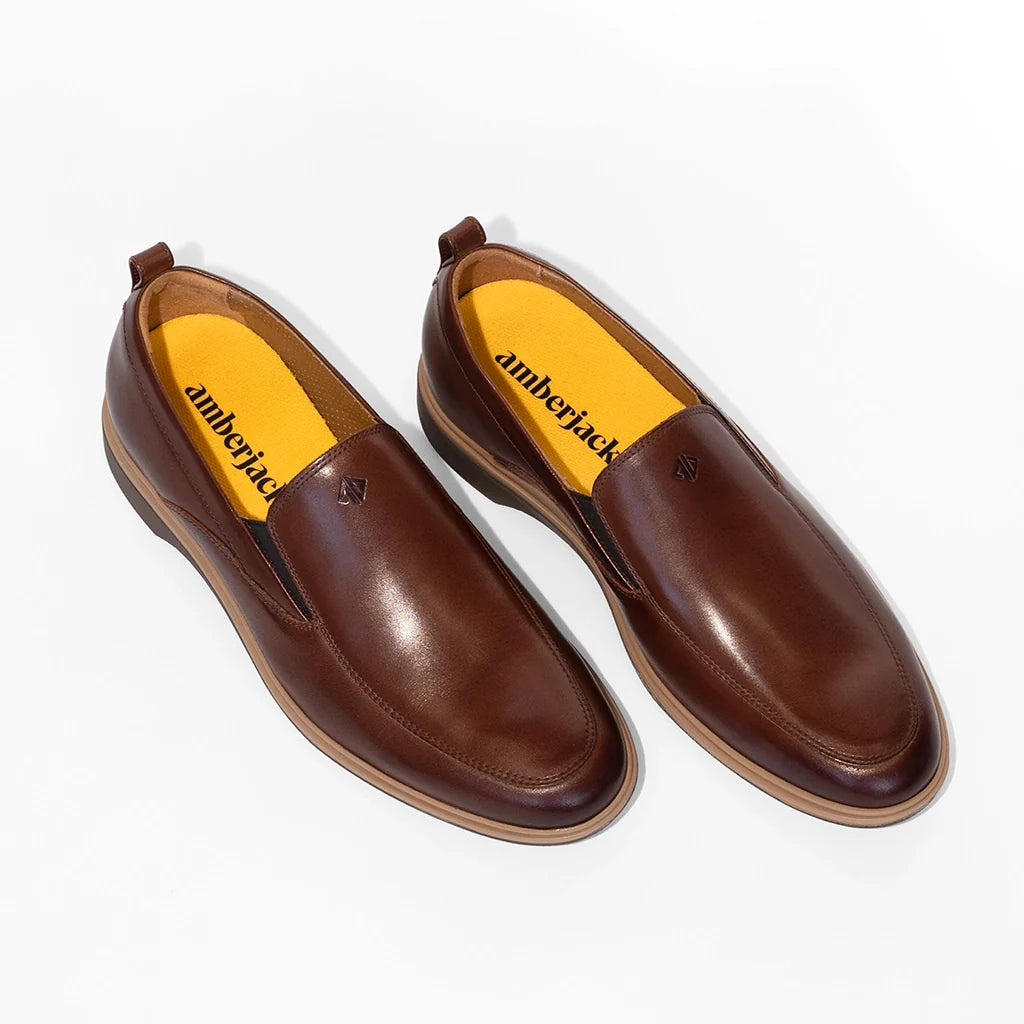 Pair of brown leather shoes with yellow soles on a white background