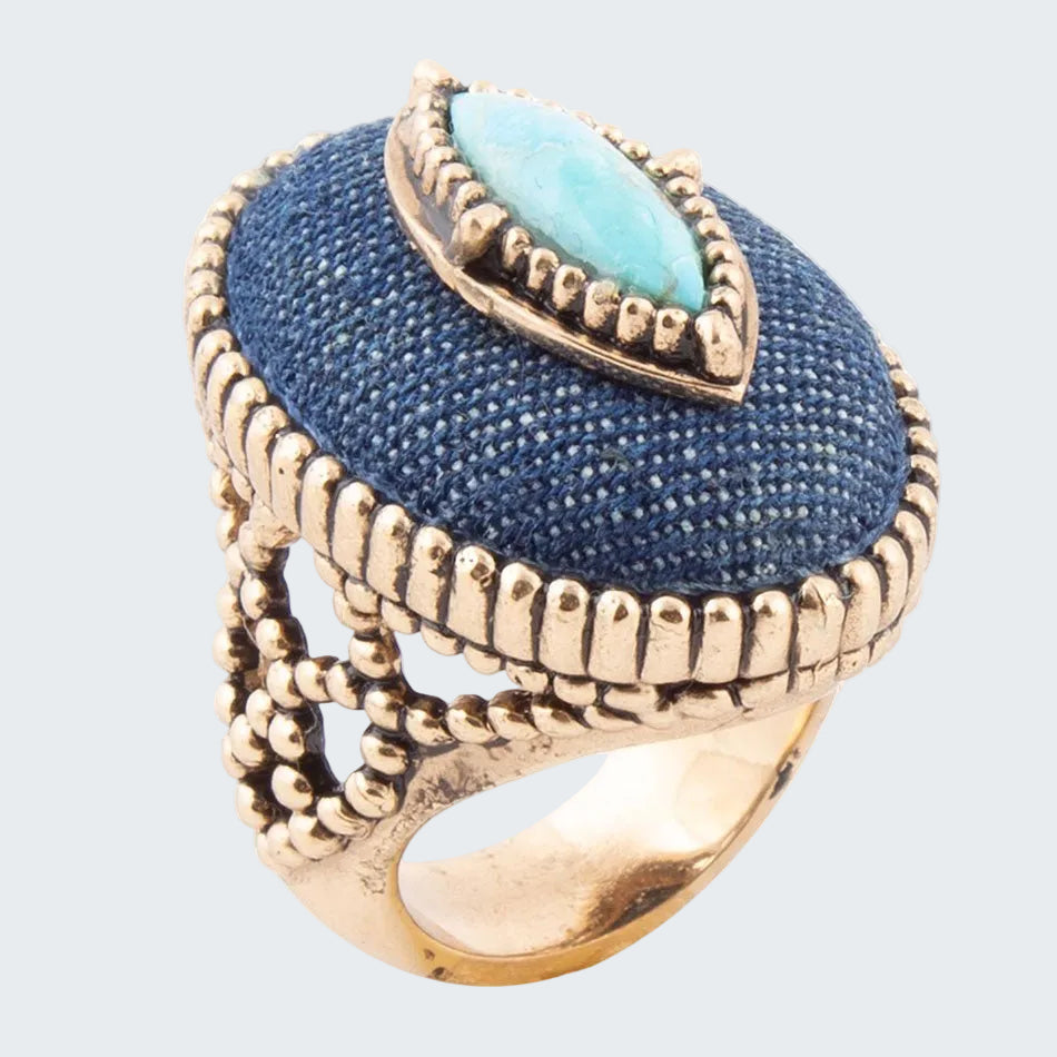 Ring with blue stone and gold detailing on a white background