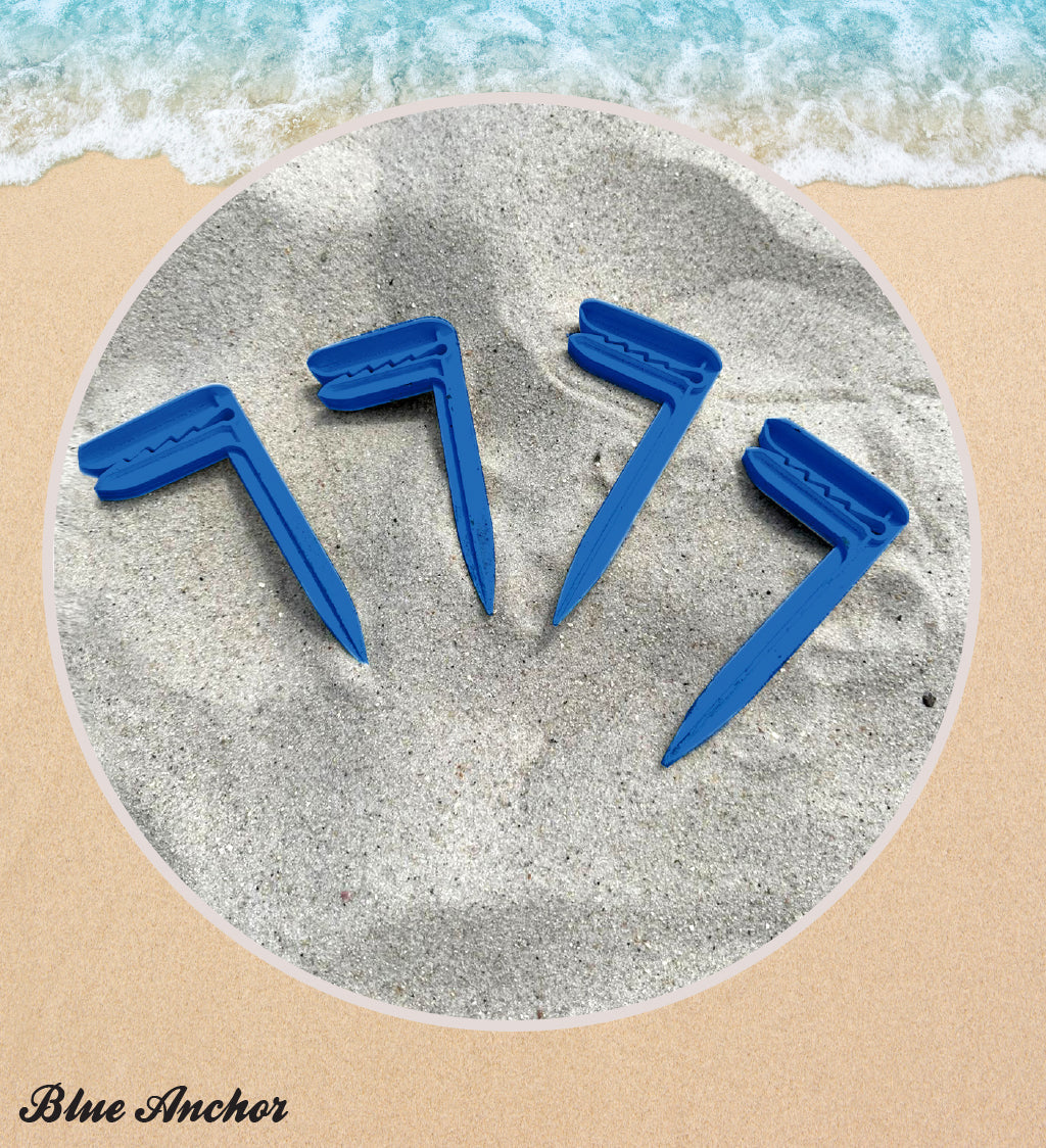 Four blue sand anchors on a sandy surface with ocean waves in the background.