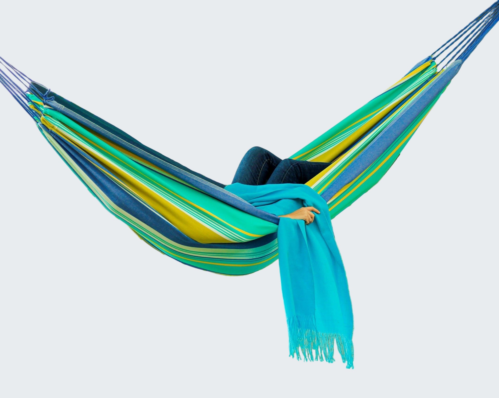 Person relaxing in a colorful striped hammock with a scenic background