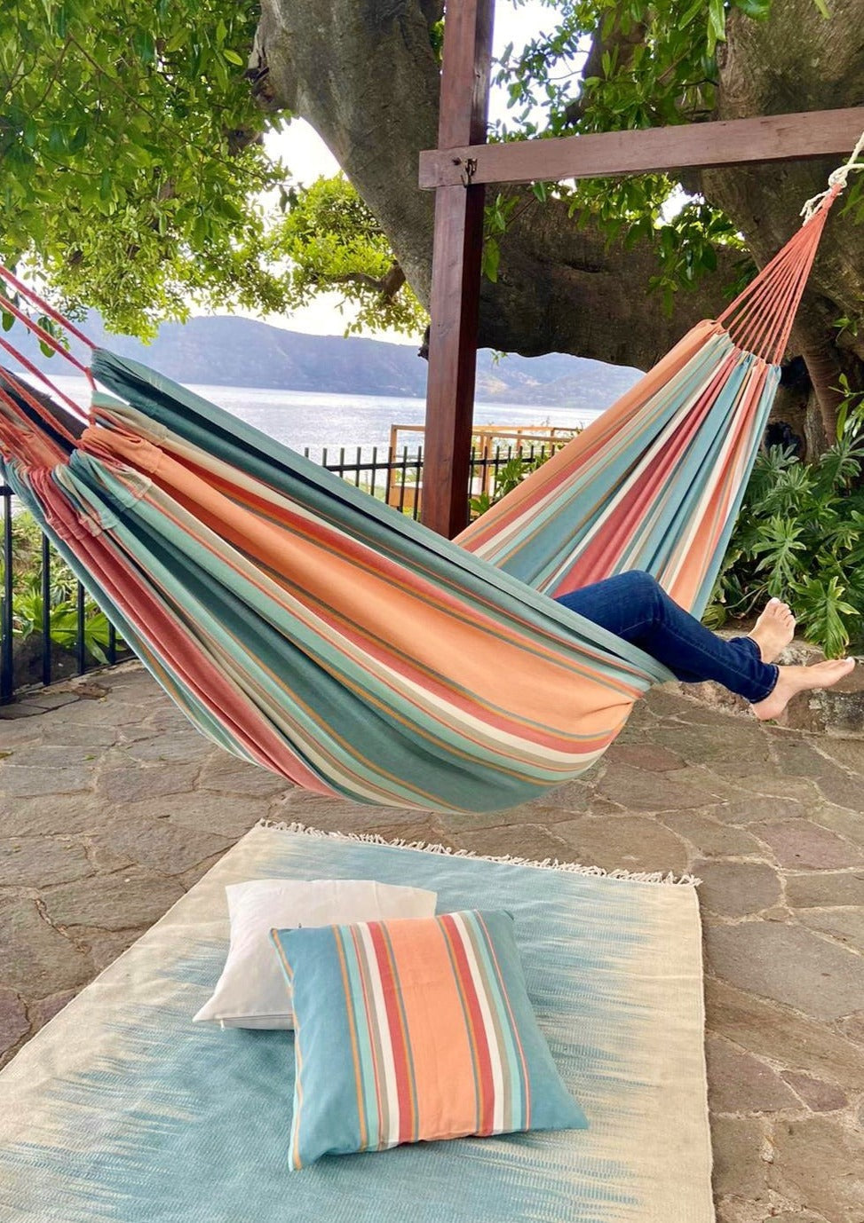 Person relaxing in a colorful striped hammock with a scenic background
