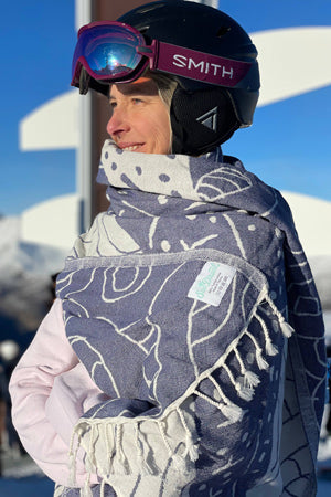 Person wearing a helmet and goggles with a branded scarf in a snowy landscape
