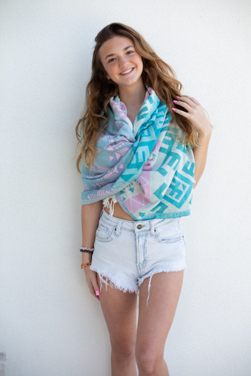 Woman wearing a colorful scarf and denim shorts against a white background