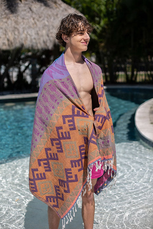 Man standing by a pool with a patterned towel draped over his shoulders