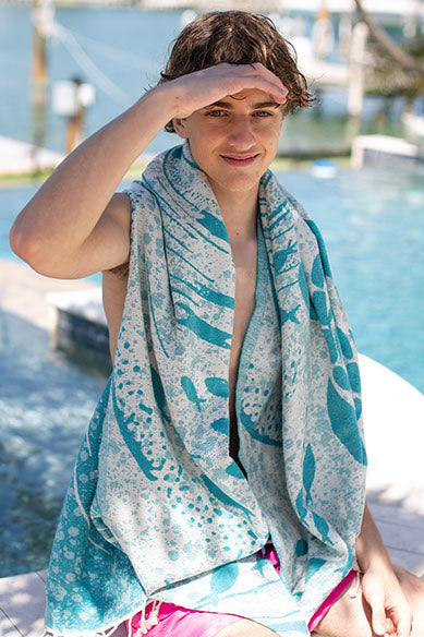 Person wrapped in a blue and white patterned towel by a marina