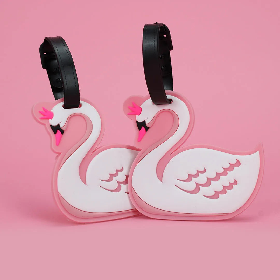 Two swan-shaped luggage tags on a pink background