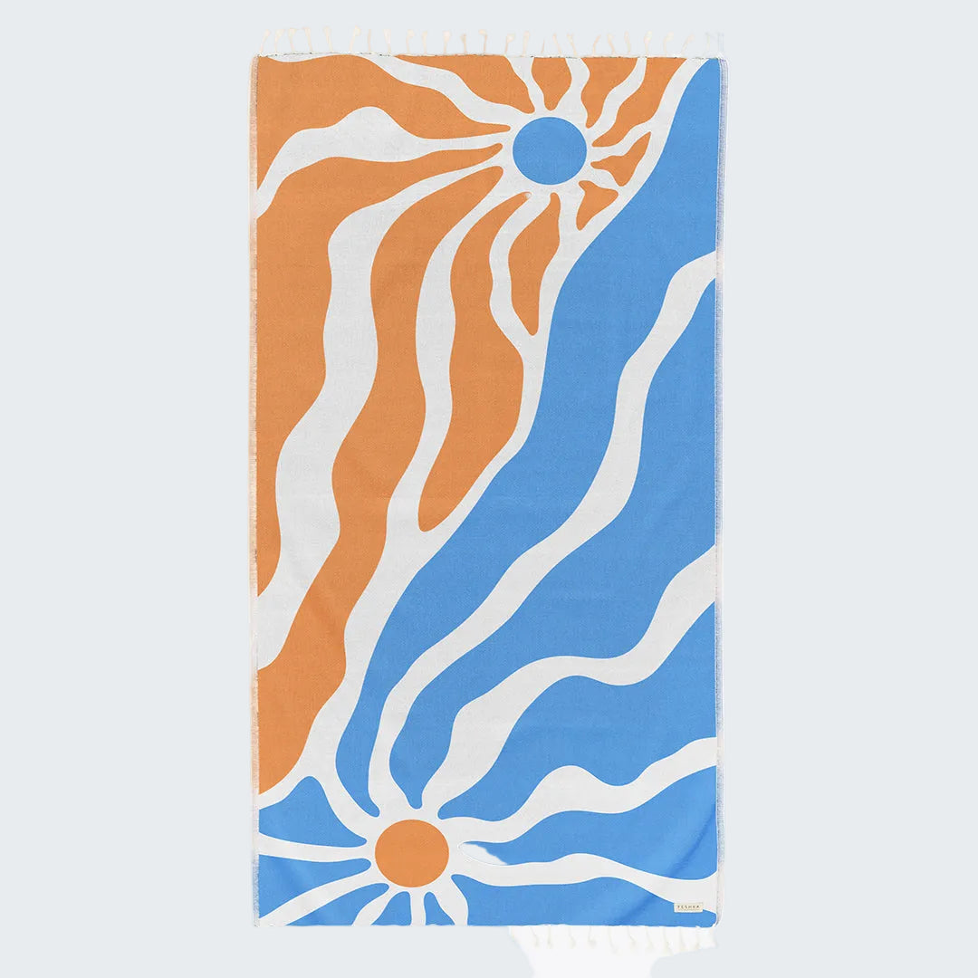 Towel with sun and wave pattern in orange, blue, and white on a white background