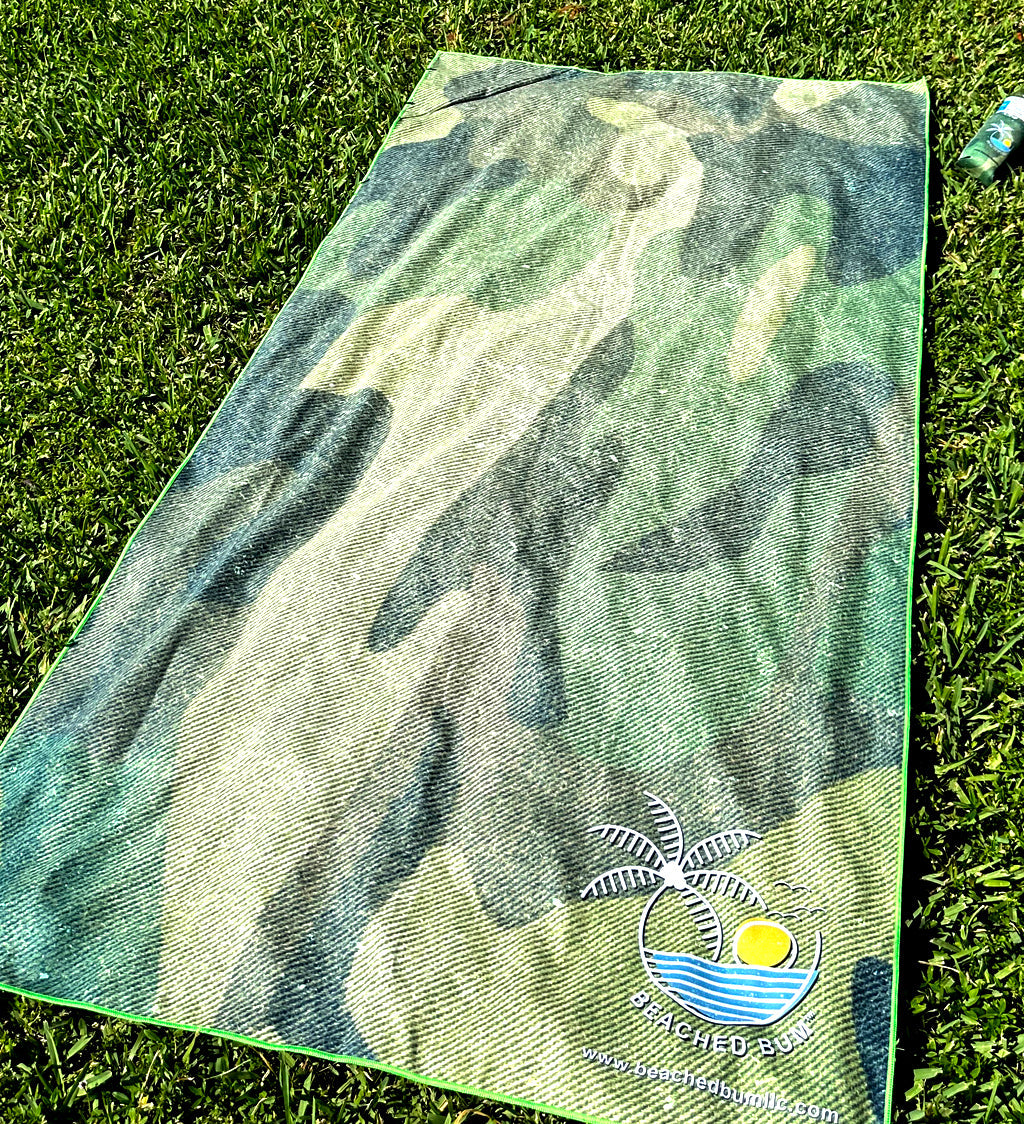 Green and blue patterned towel with a palm tree design on grass