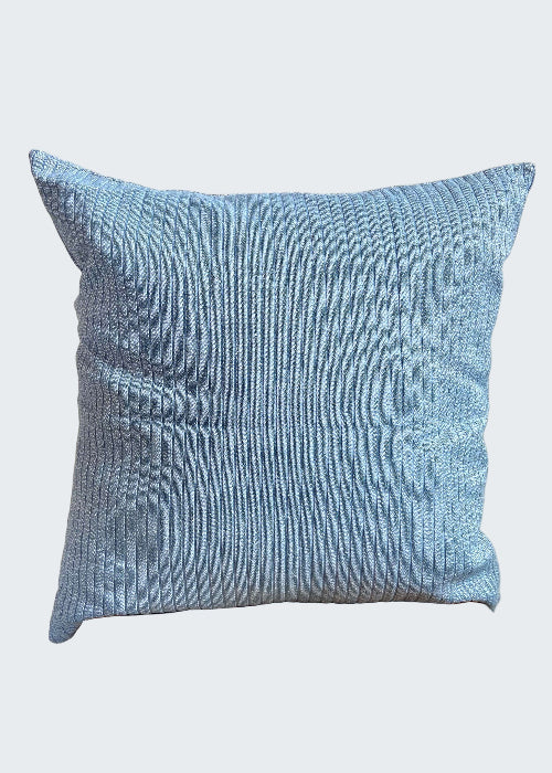 Blue textured pillow on a wooden stool against a light background