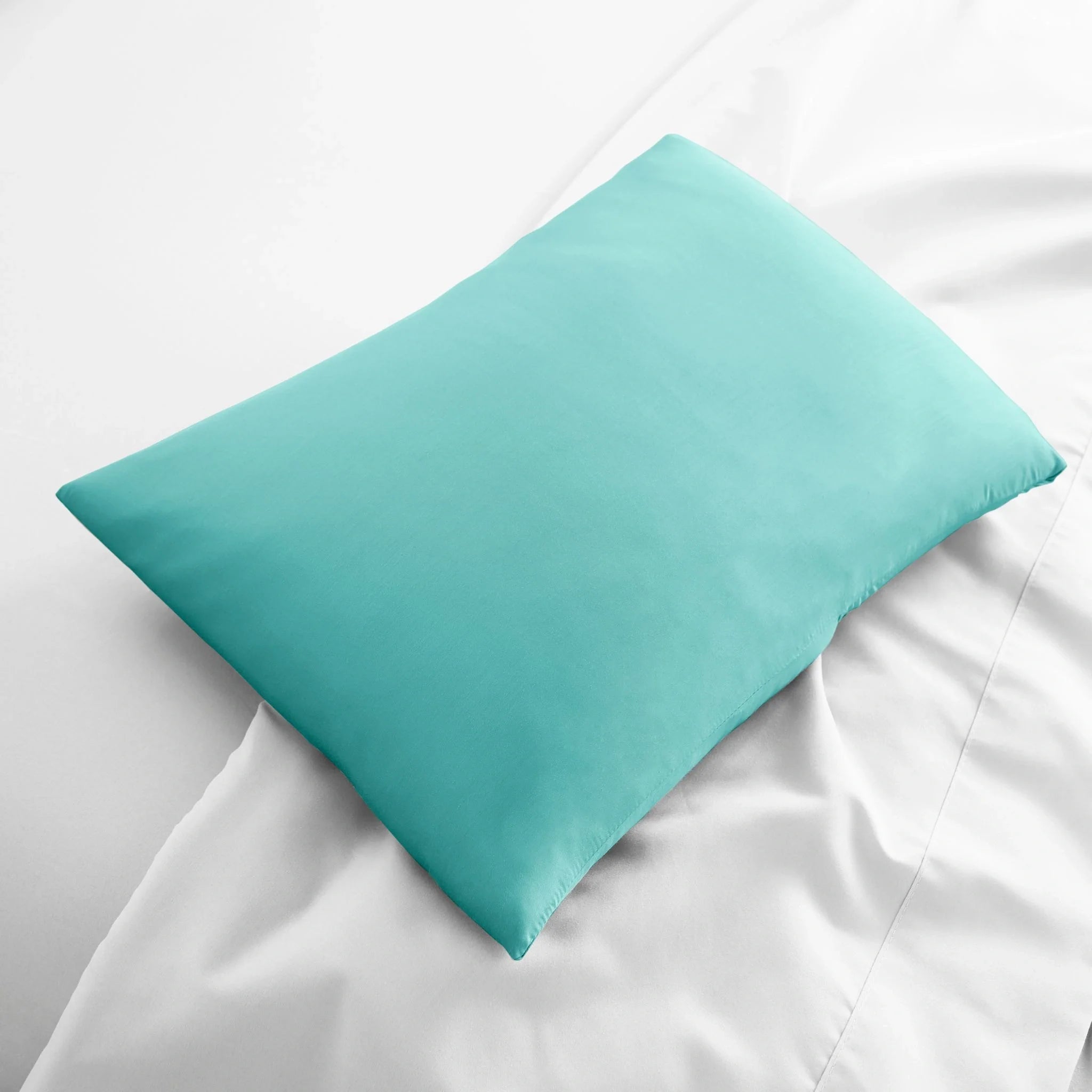Teal pillow on a white bed